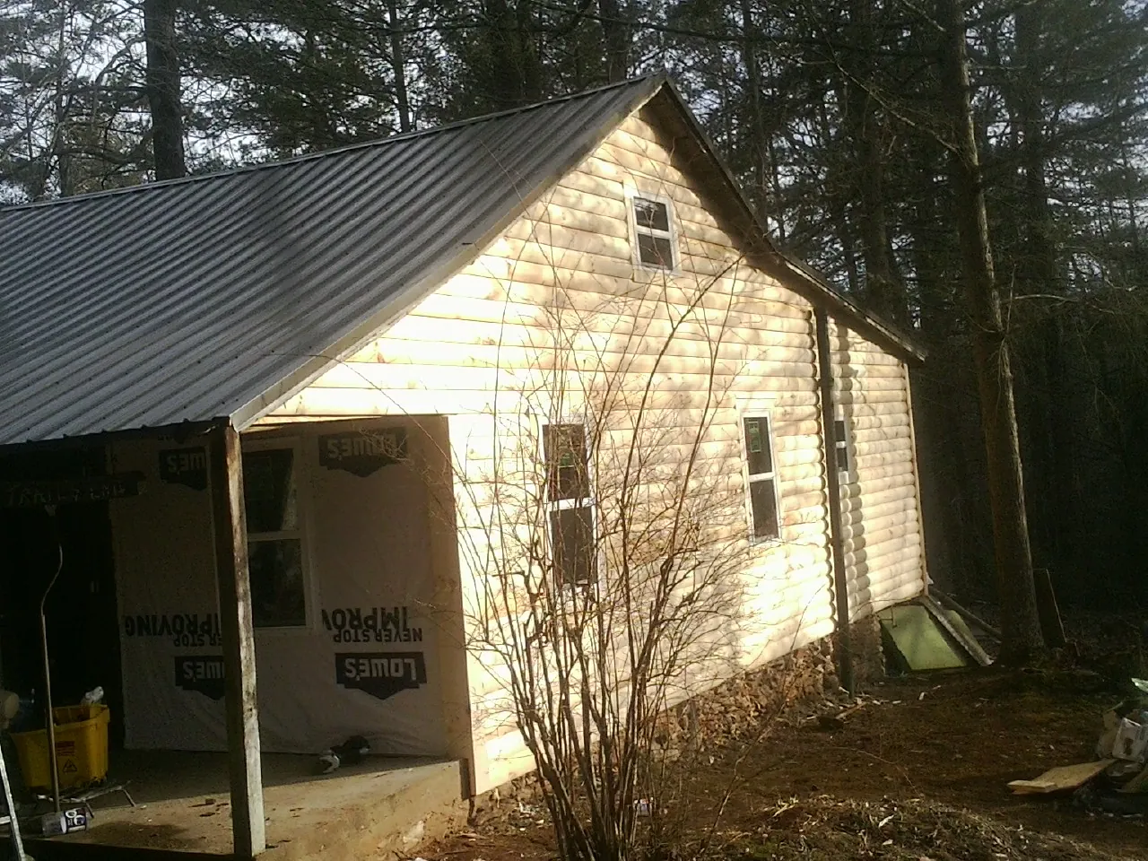 Log siding gable end under a dark metal roof edge in Dennis