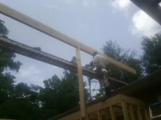 Carpenter setting a ridge beam over a new addition frame — Ice Dam Removal by Roofing Brothers in Dennis