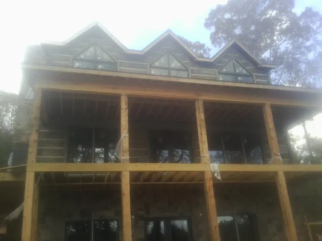 Dormers and porch framing on a large log home under construction — Roof Coating work by our crew in Dennis